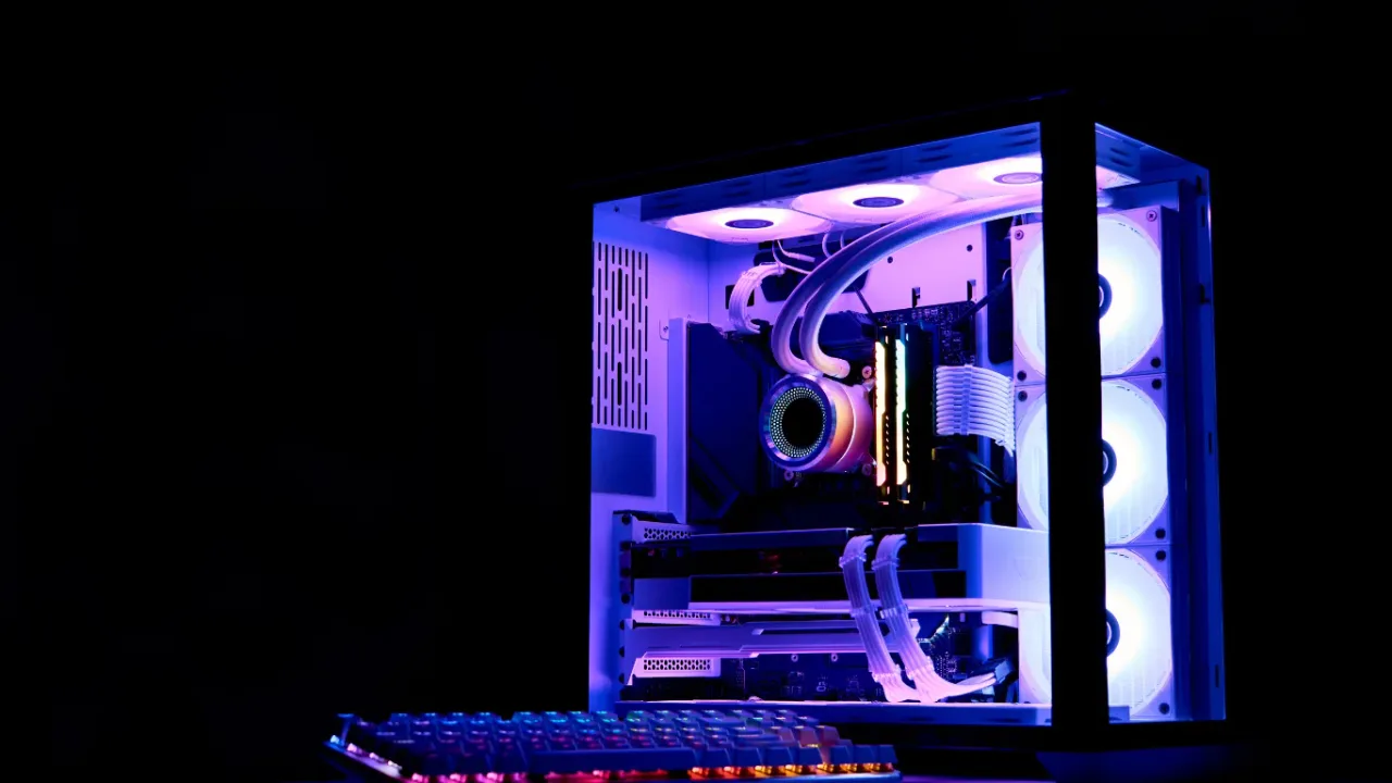 A high-end custom gaming PC build with a transparent side panel glowing with vibrant purple and blue RGB lighting, showcasing internal components and cooling fans next to an illuminated mechanical keyboard, representing the hardware power needed to fully optimize your first game settings.