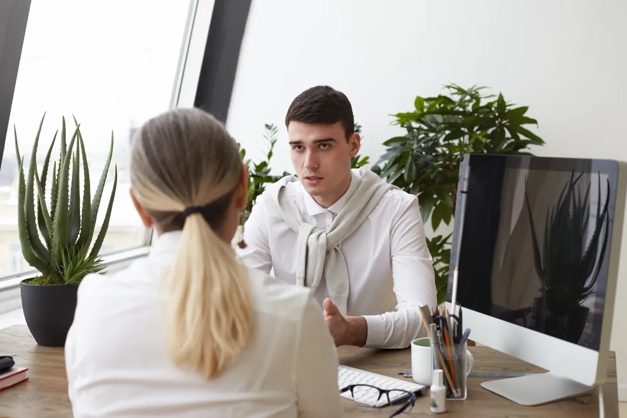 handsome serious young man hr specialist interviewing unrecognizable female with ponytail job interview asking questions about her experience skills employment human resources