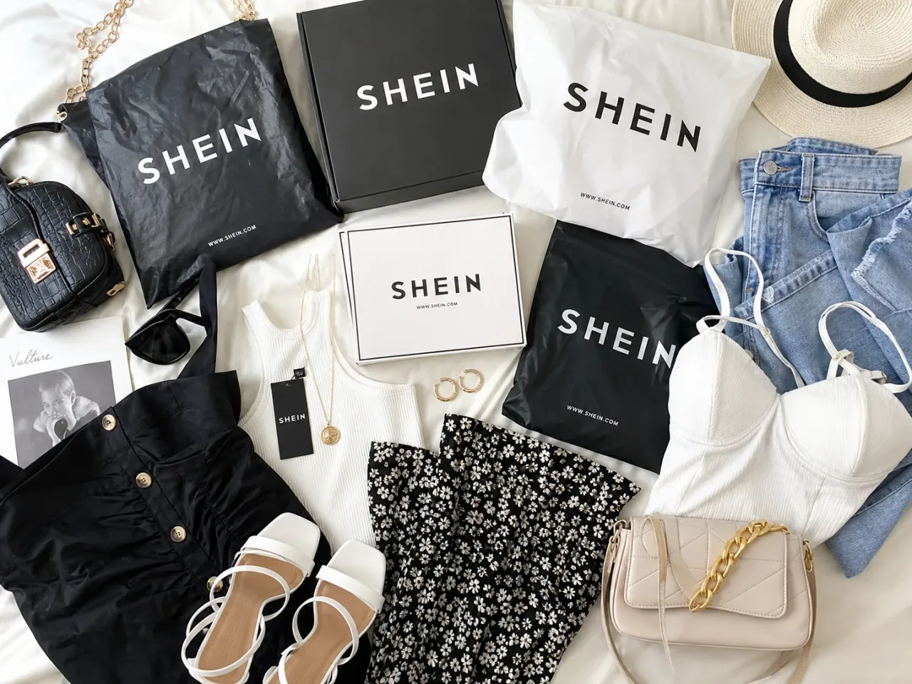 Produtos e pacotes da Shein dispostos sobre uma mesa. A imagem representa o passo a passo para participar do Teste Gratuito da Shein.