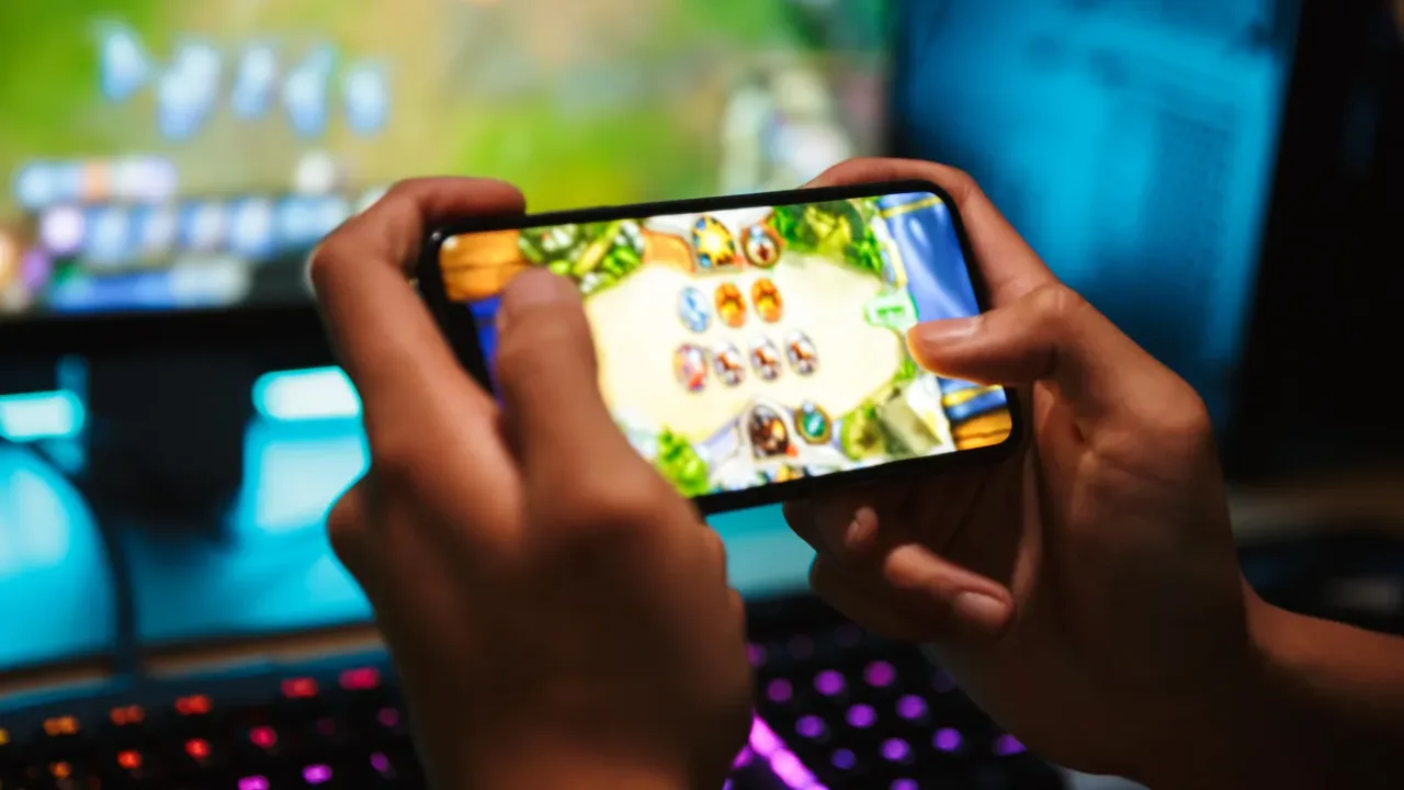 Hands holding a smartphone while playing a colorful game, highlighting the Mobile Gaming experience.