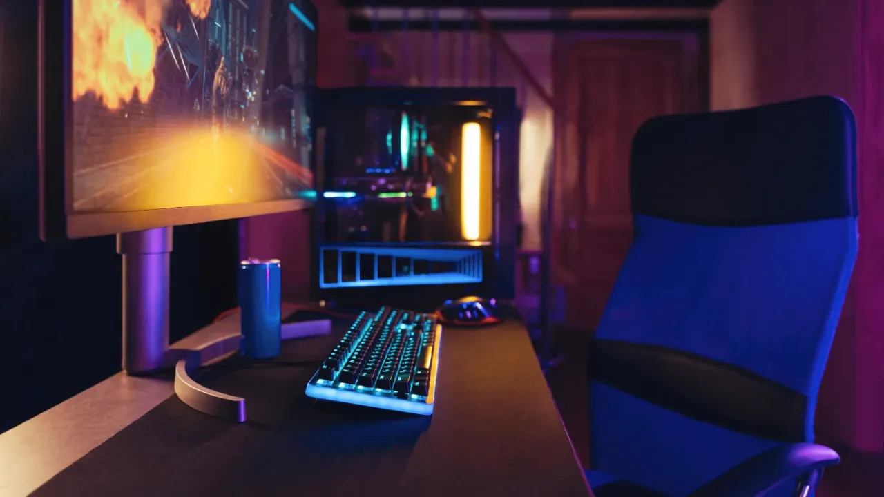 Gaming Desk Setup with an RGB-lit PC, monitor, keyboard, mouse, and ergonomic chair in a modern gaming room.