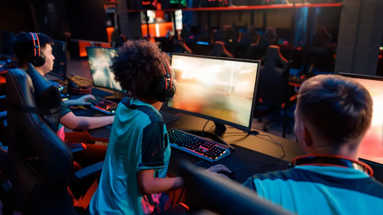 Gamers playing on high-performance PCs in an esports arena during a Gaming Network Setup session.