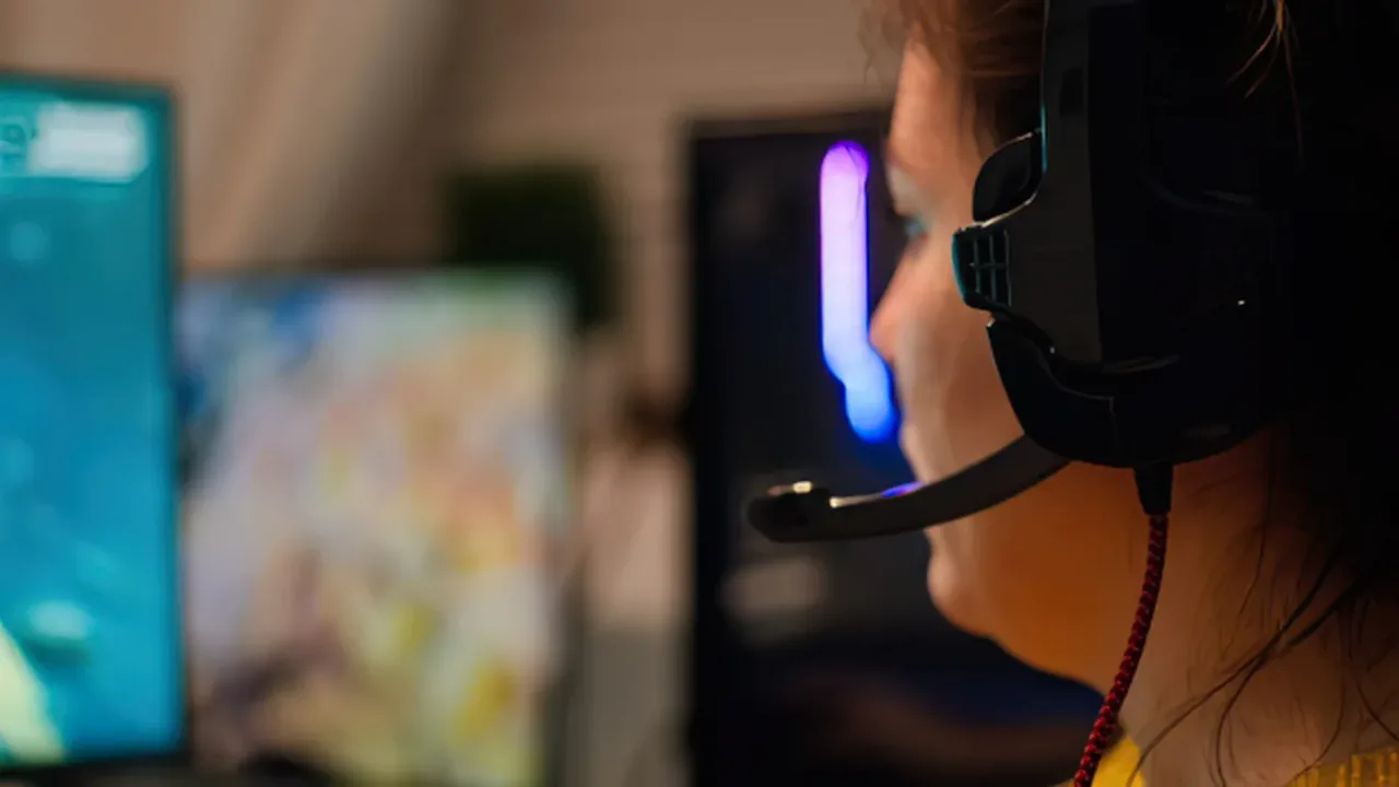 Gaming Headset worn by a player focused on gameplay, with a boom microphone and illuminated gaming setup in the background.