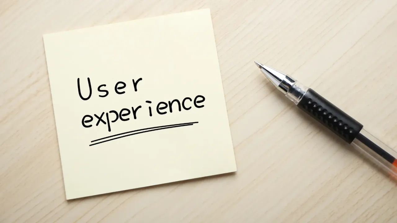 Sticky note with the words 'User experience' next to a pen on a wooden desk, illustrating a User Content Framework for improving digital content and user engagement.