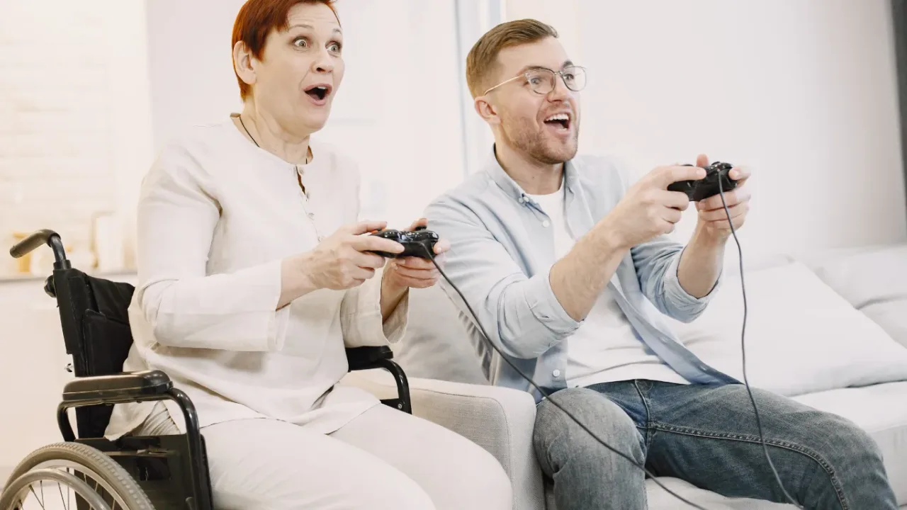 Two people enjoying video games with controllers, highlighting inclusive Game Accessibility for players with different needs.