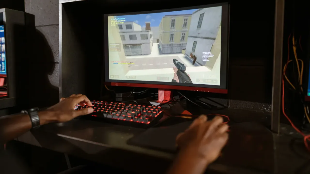 Gamer using a keyboard and mouse to play a first-person shooter with Performance Mode enabled on a gaming PC.