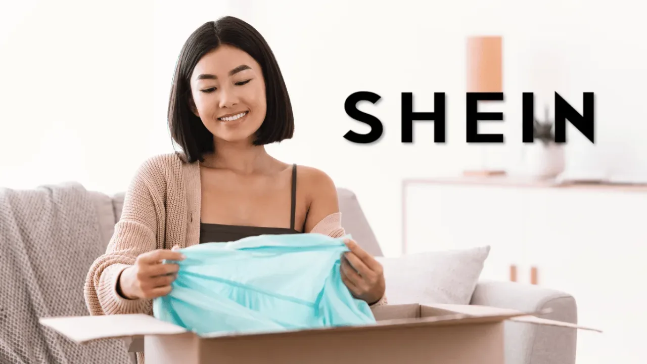 A happy woman sits on a couch while unwrapping a package, excitement glowing as she envisions the possibilities of her new Free SHEIN Clothes.
