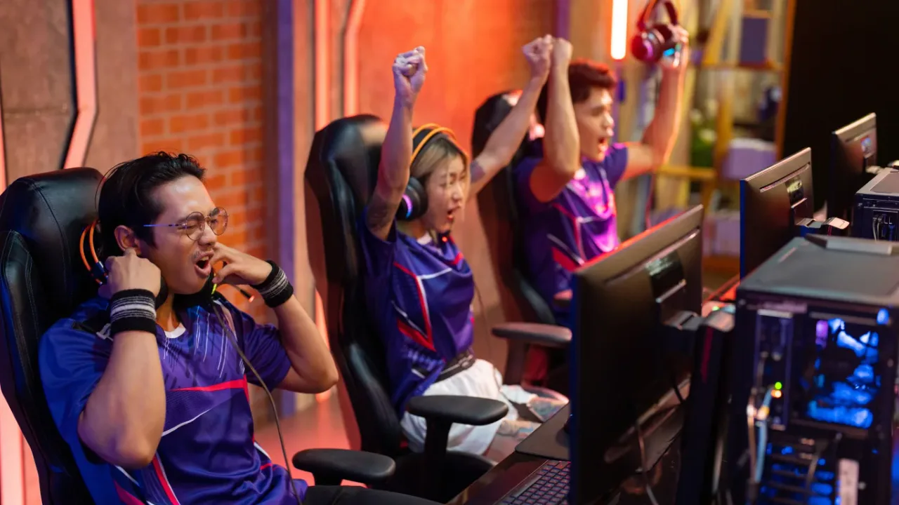 Esports players celebrate a victory at their gaming stations as Team Ownership Rules Updated reshape the competitive scene.