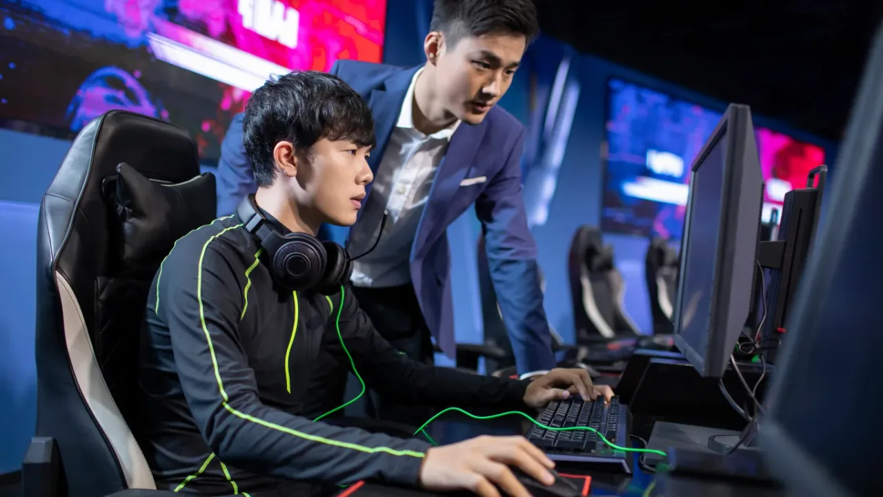 An esports player receives focused Performance Coaching from a coach while competing at a gaming station.