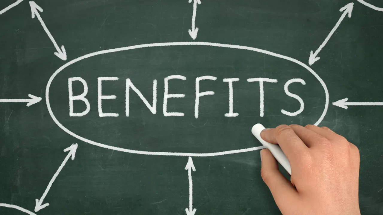Hand holding chalk beside the word “BENEFITS” on a chalkboard with arrows pointing toward it, illustrating the advantages of a Player Benefits Program.