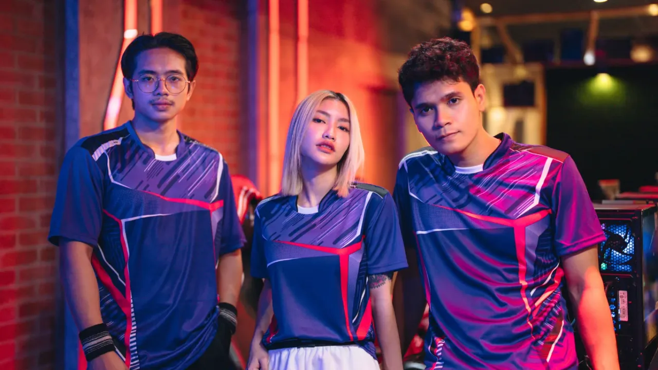 Three esports players in matching jerseys pose together in a gaming venue, representing esports team formation.