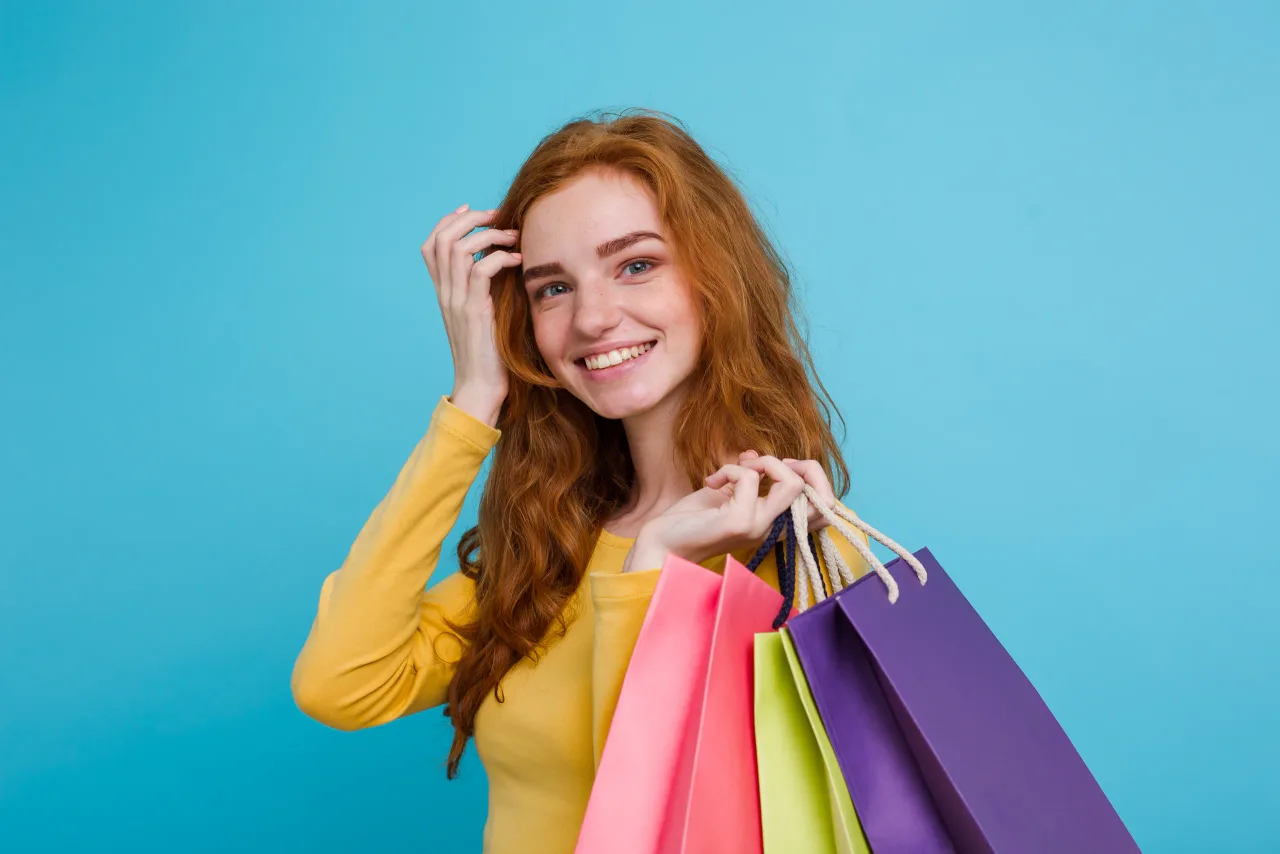 shopping concept close up portrait young beautiful attractive redhair girl smiling looking camera with shopping bag blue pastel background copy space